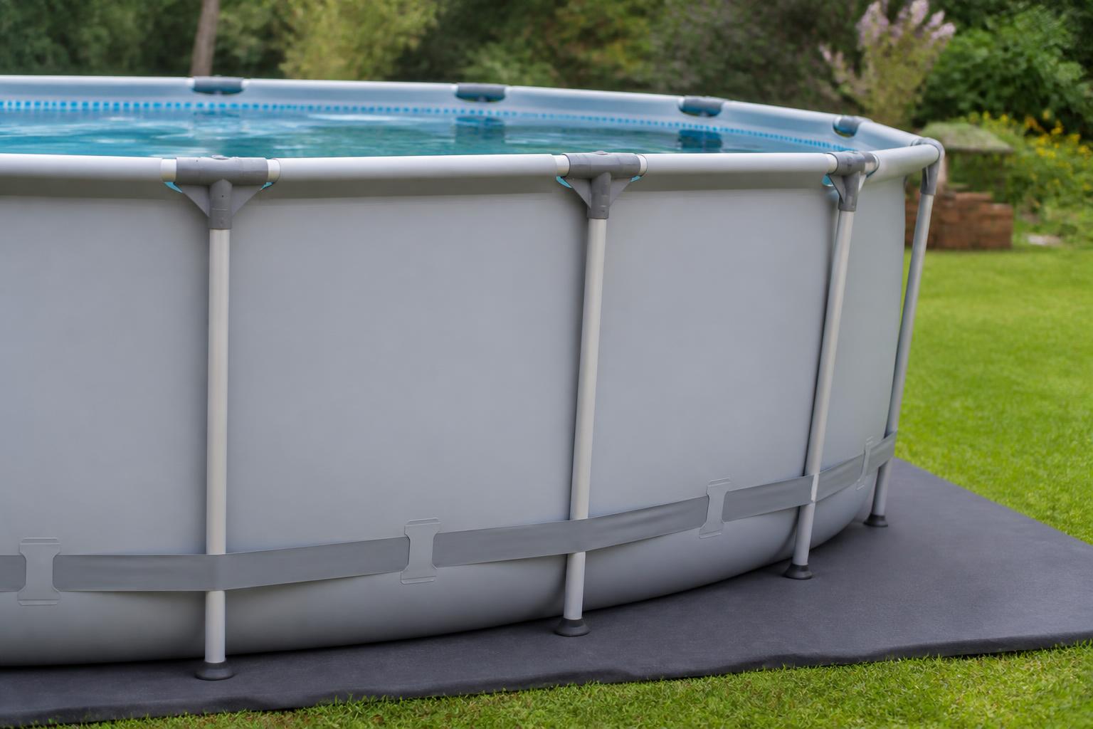 Une piscine hors sol tubulaire montée sur un tapis de sol, structure en tubes d'acier visible autour du bassin